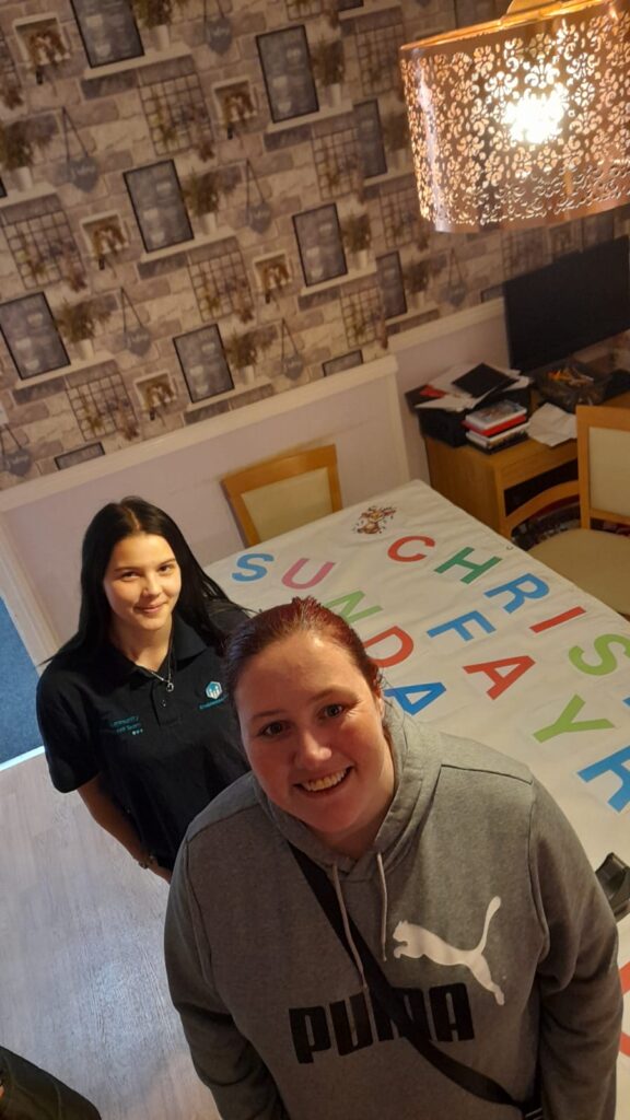 staff member and service user with their banner laid across a table inside