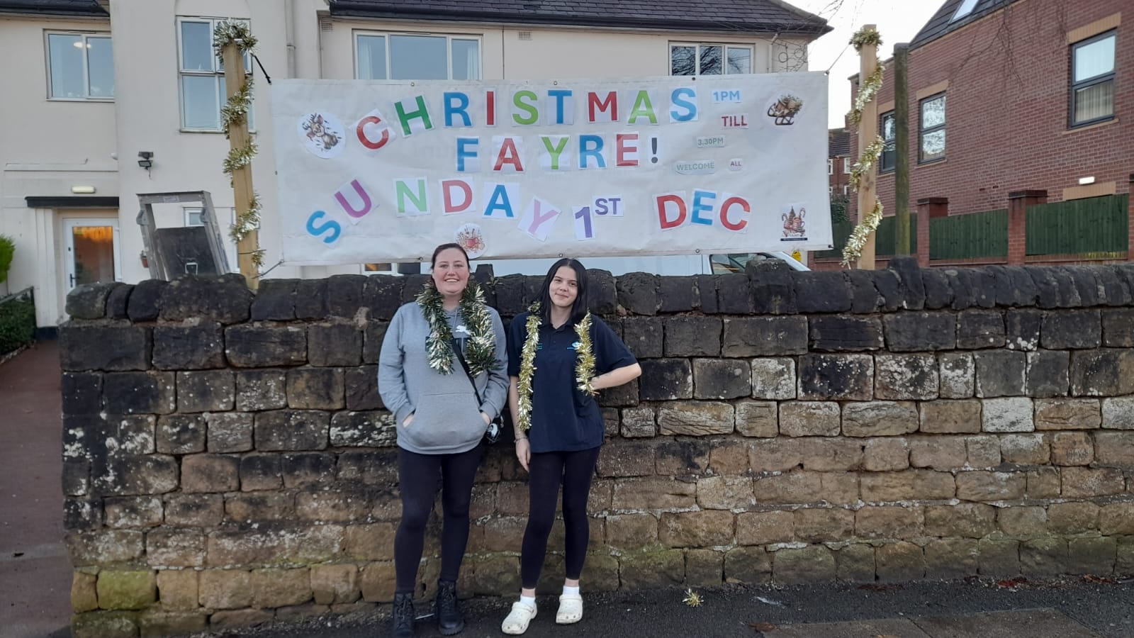 Staff member and service user standing with their banner outside enablement care