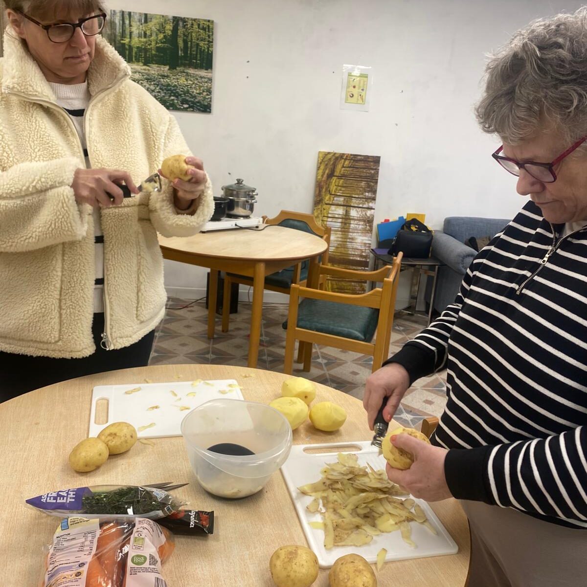 Two people preparing potatoes at a table.