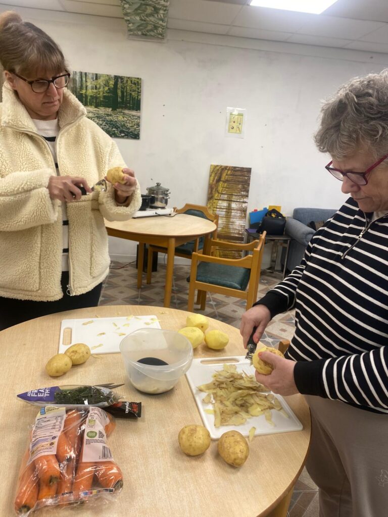 Two people preparing potatoes at a table.