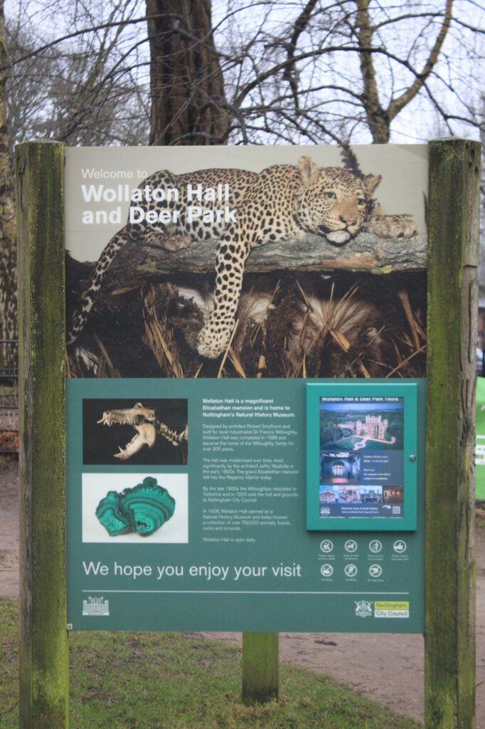 An informational sign at Wollaton Hall and Deer Park featuring an image of a leopard and details about the hall being home to Nottingham's Natural History Museum.