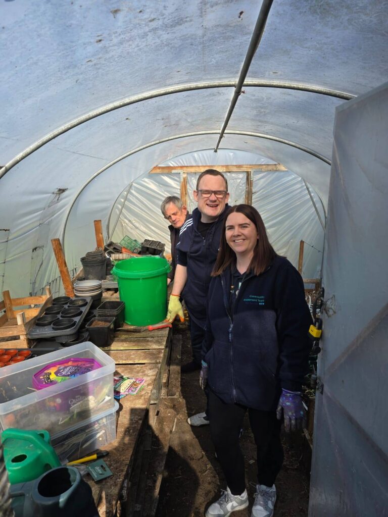3 gardening club members in the polytunnel at the allotment.